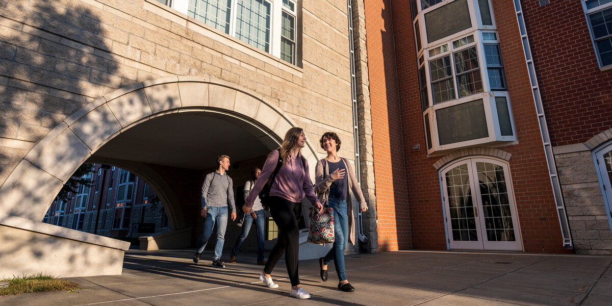 Students walk under arch in suite apartments