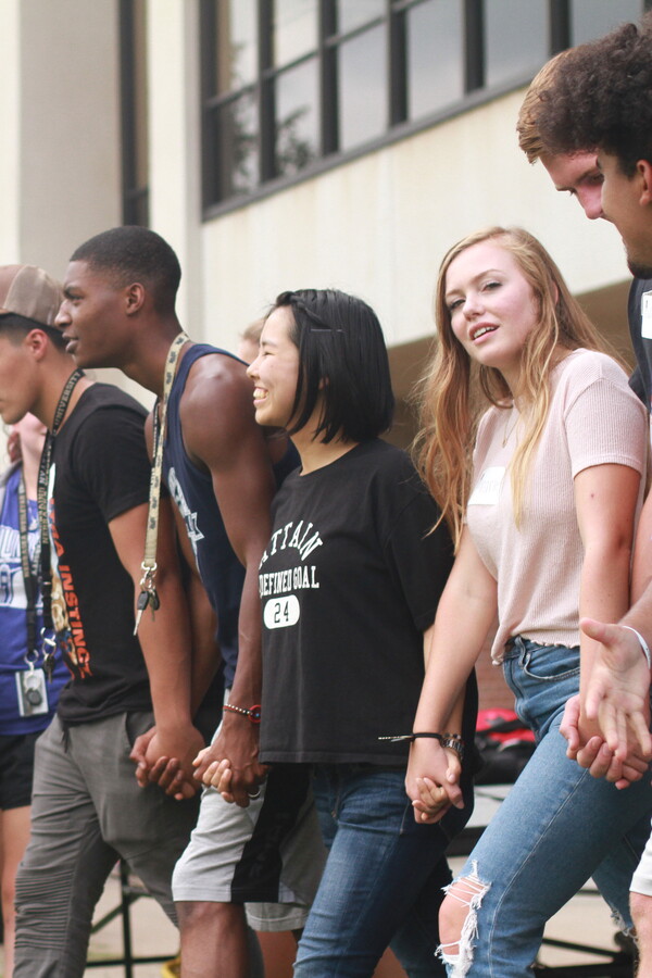 A group of students holding hands and smiling broadly.