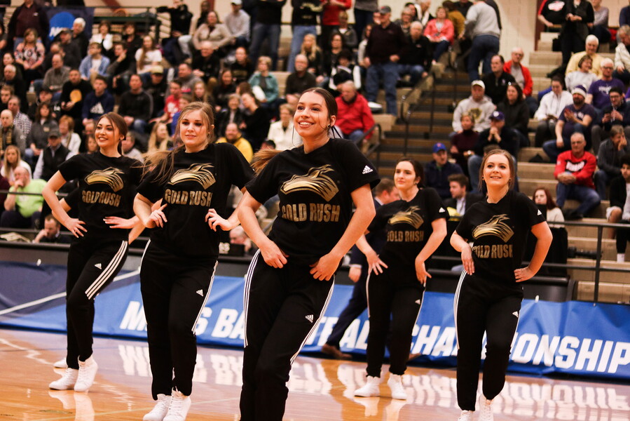 Five females of the Gold Rush dance team perform during half-time at a basketball game..